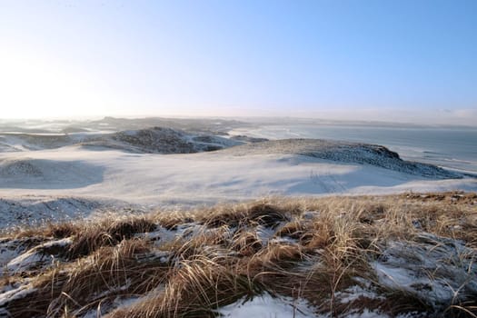 snow covered links golf course in ireland in winter with sea background