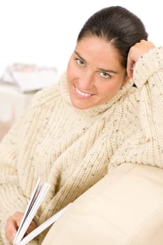 Happy mid-aged woman read book sitting on couch