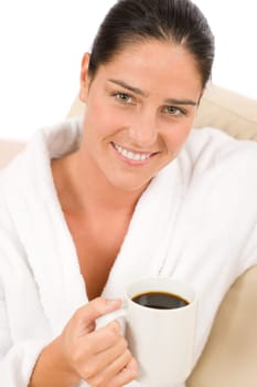 Attractive woman in white bathrobe with coffee in lounge