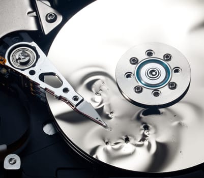Magnetic disc inside a damaged computer hd unit showing mirror surface of the magnetic discs and read write head
