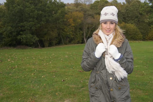 Pretty teenage girl wearing hat, scarf and gloves enjoying a walk in the countryside