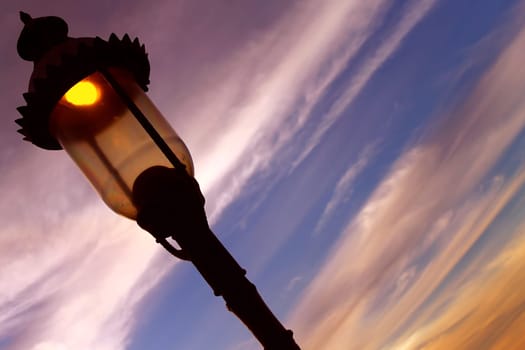 A street lamp turning on during the sunset to light the night