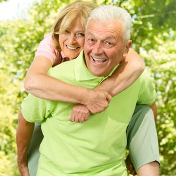 Portrait of happy senior man giving piggyback ride outdoors.