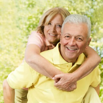 Portrait of happy senior man giving piggyback ride outdoors.