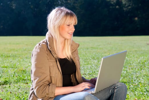 Young woman with laptop in a meadow