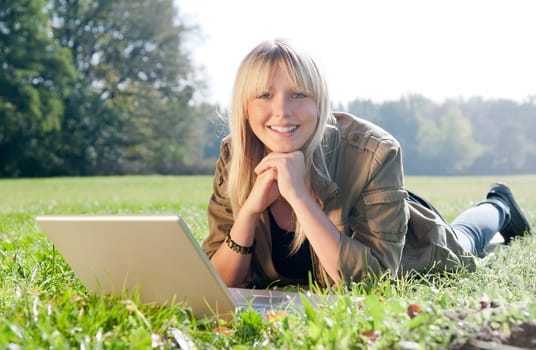 Young woman with laptop in a meadow