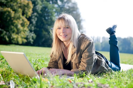 Young woman with laptop in a meadow