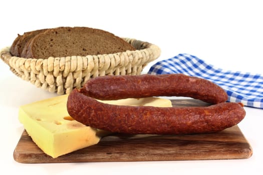 Two salamis with cheese and bread against white background
