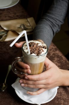 Closeup of female hands holding cup of latte