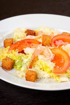 Salad of tiger shrimps, lettuce, chinese cabbage, tomato, garlic rusk, parmesan cheese and sauce