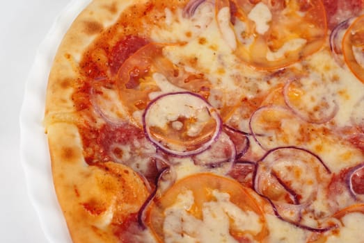 pizza closeup with salami, tomato, onion and mozzarella cheese