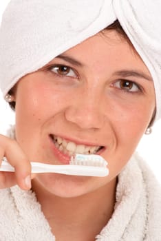 Isolated image of a cute girl with a towel around her head brushing her teeth