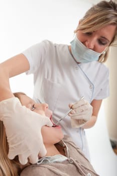 Dentist inspecting the teeth of a young girl