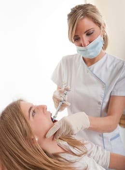 Female dentist injecting anesthetics to a young patient