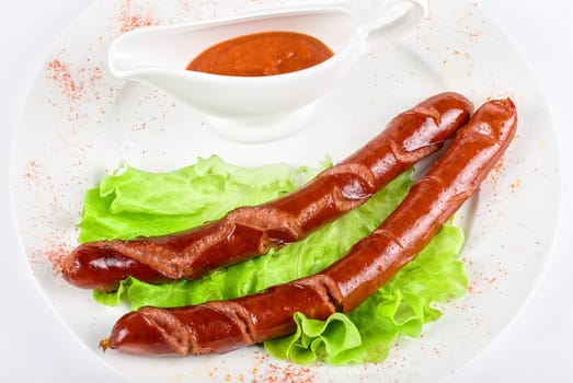 grilled sausage closeup with lettuce and sauce isolated on white