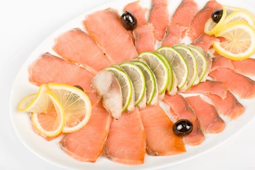 Sliced chum salmon and mackerel closeup decorated with limes, lemons and olives