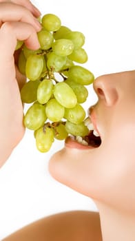 Closeup of woman mouth with green grapes on a white