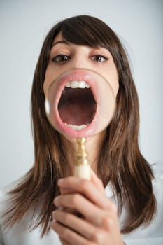 Young woman showing her mouth thru a magnifying glass