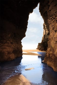 a view from the inside of a beach cave looking out at the sea