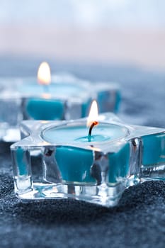 Close-up of blue candles in star shape holders on silver sand