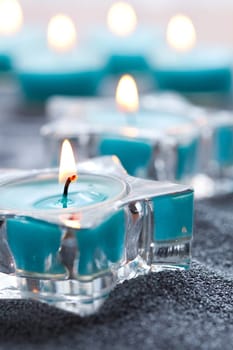 Close-up of blue candles in star shape holders on silver sand