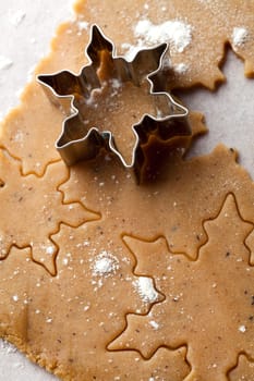Making gingerbread cookies for Christmas. Gingerbread dough with star shapes and a cutter.
