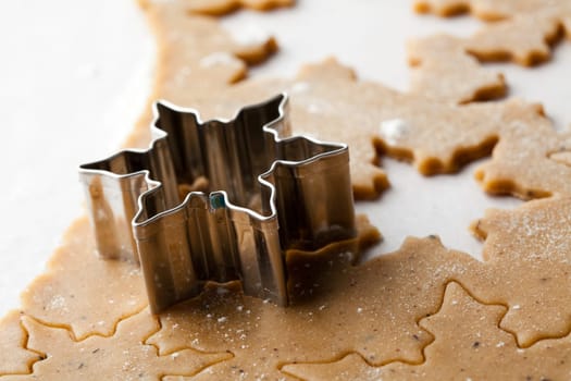 Making gingerbread cookies for Christmas. Gingerbread dough with star shapes and a cutter.