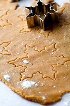 Making gingerbread cookies for Christmas. Gingerbread dough with star shapes and a cutter.