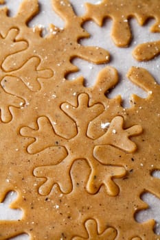 Making gingerbread cookies for Christmas. Gingerbread dough with snowflake shapes.