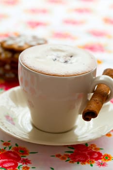 Close-up of delicious hot chocolate with chocolate sprinkles, cinnamon stick and gingerbread cookies