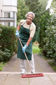 Active senior woman with a broom