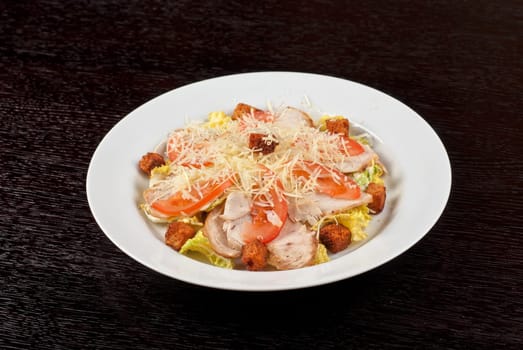 Salad of lettuce, chinese cabbage, tomato, garlic rusk, parmesan cheese, sauce and chicken meat