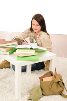 Student girl studying home sitting on floor with books