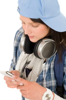 Smiling female teenager enjoy music with headphones dialing on phone