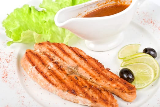 Grilled salmon steak with sauce,greens, lemon and olive