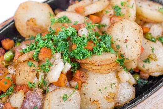 Fried potato with meat and vegetables on a white