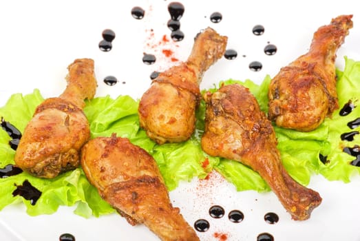 chicken drumstick closeup at white plate with lettuce