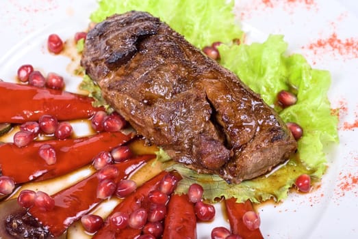 Roasted beef steak with pomegranate closeup at plate