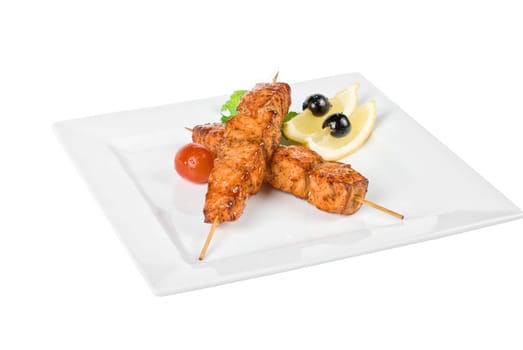 salmon kebab at plate with green lettuce and lemon on a white
