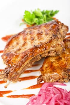Cooked pork chop with kiwi and parsley on a white
