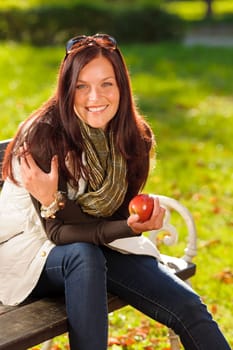 Autumn fashion smiling beautiful woman eat apple sunset nature park