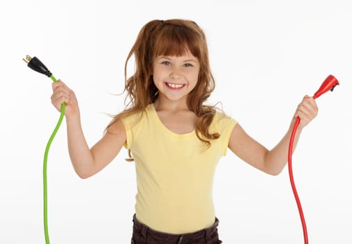 Waist up front view of female child holding two electrical cords, on white background.