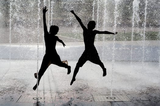 silhouette of kids jumping in cool fountain water
