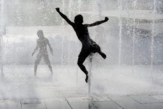 happy wet summer kids playing in water fountain
