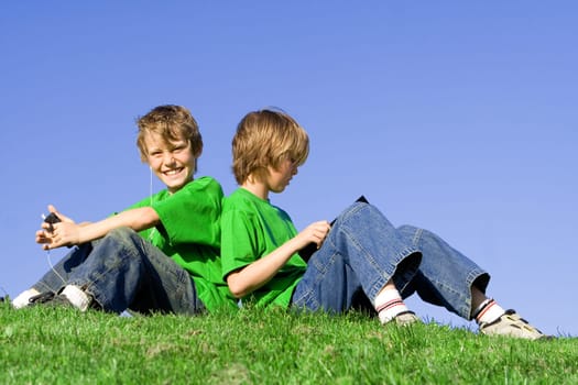 kids outdoors in summer, reading and listening to music