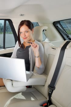 Executive woman manager working on laptop sitting car leather backseat