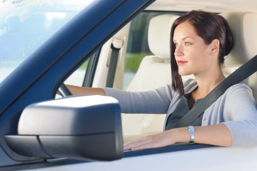 Attractive elegant businesswoman driving luxury new car concentrating