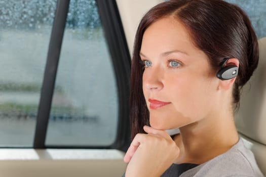 Attractive executive female manager sitting in car backseat calling hands-free
