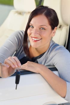Attractive elegant businesswoman in new car showing keys smiling