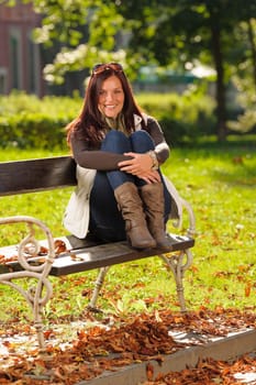 Autumn fashion outfit attractive woman sitting on park bench sunset